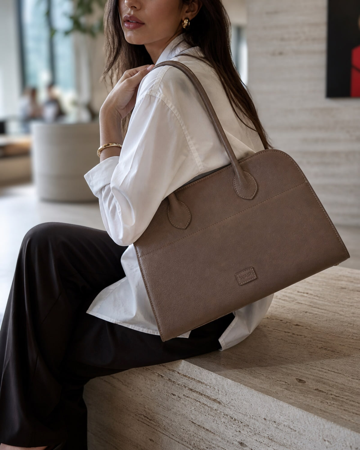 The Bridge in taupe leather carried at the shoulder in an interior setting